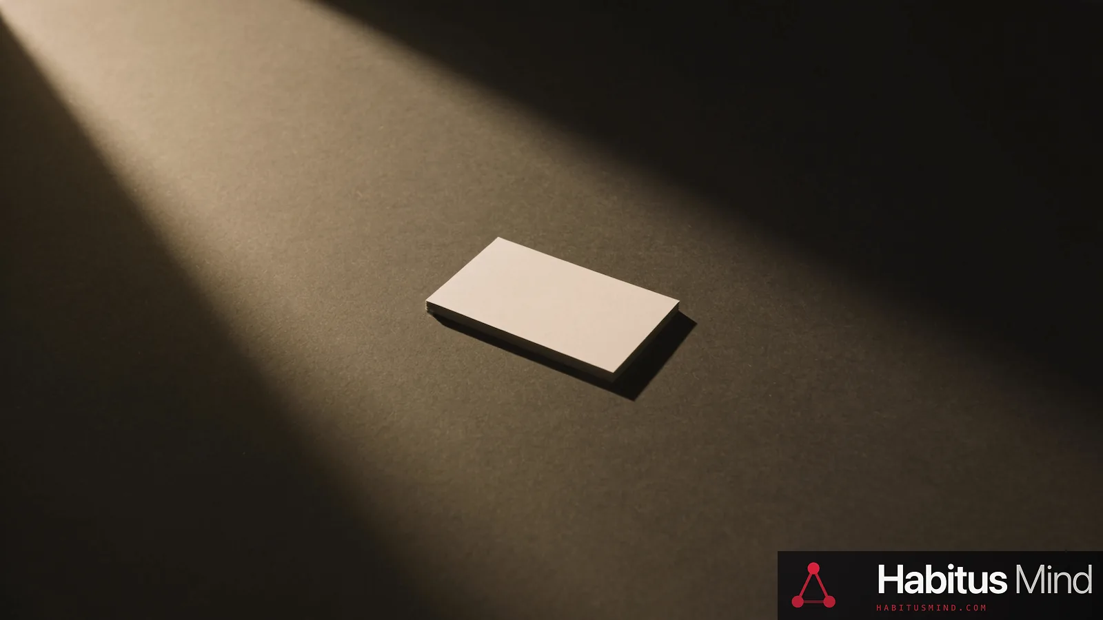 A single blank business card alone in the centre of a large empty dark desk